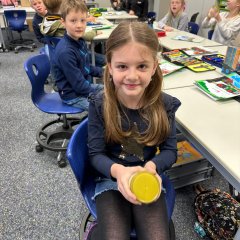 Ein Kind schüttelt ein Schraubglas mit Sahne bis Butter entsteht.