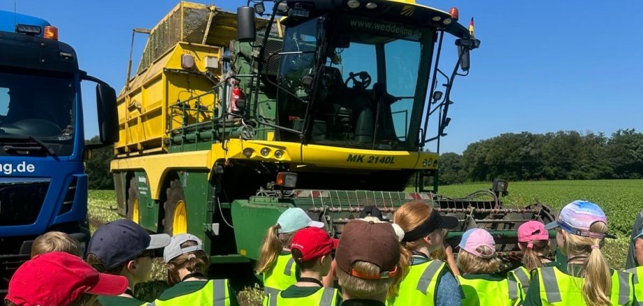 Kinder stehen vor einer Spinat-Erntemaschine