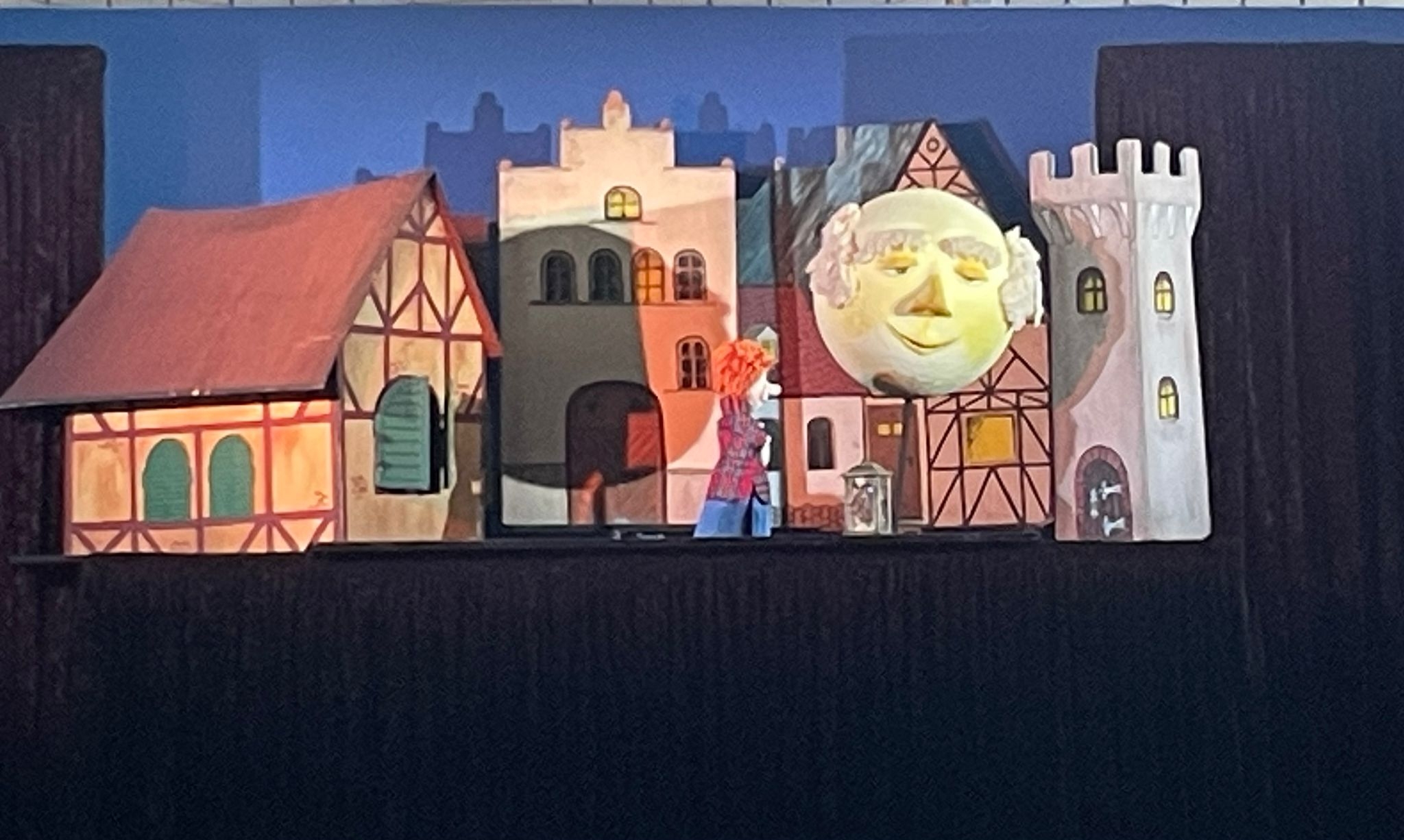 Die Bühne des Puppentheaters "Die Mondlaterne" mit kleinen Häusern und einem großen Mond.