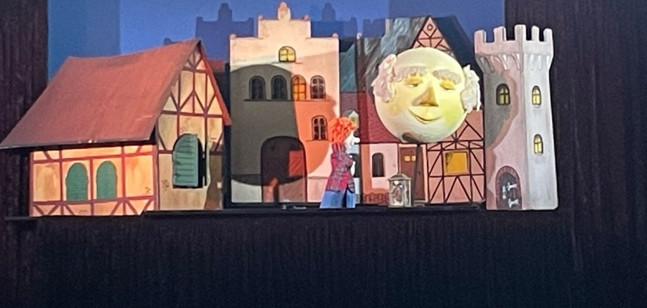 Die Bühne des Puppentheaters "Die Mondlaterne" mit kleinen Häusern und einem großen Mond.