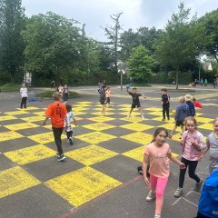 Kinder vertreiben sich die Wartezeit mit Spielen auf dem großen Pausenhof.