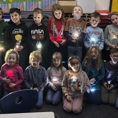 Kinder der zweiten Klasse mit Taschenlampen.
