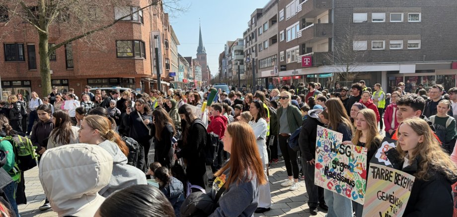 Schüler*innen mehrerer Schulen aus Gronau versammeln sich auf dem Kirchplatz zur gemeinsamen Kundgebung und halten dabei Transparente hoch: "Gegen Rassismus", ""Farbe bekennen", "Gemeinsam für Vielfalt"