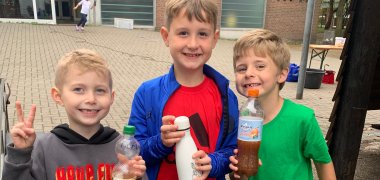 Drei Jungen zeigen ihren gepressten Apfelsaft