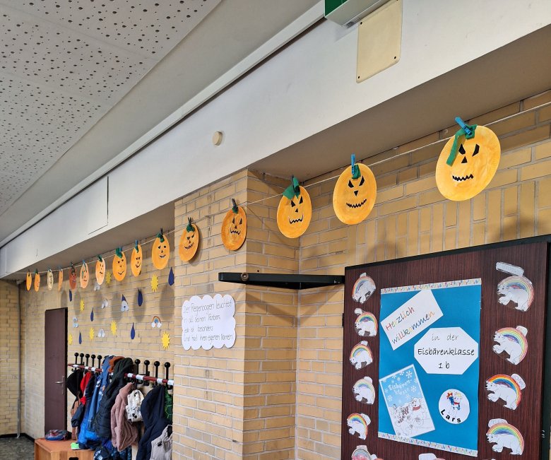 Gebastelte Kürbisgesichter hängen an einer Leine im Schulflur, Halloween Deko