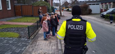 Polizist erklärt Kindern das richtige Überqueren der Straße