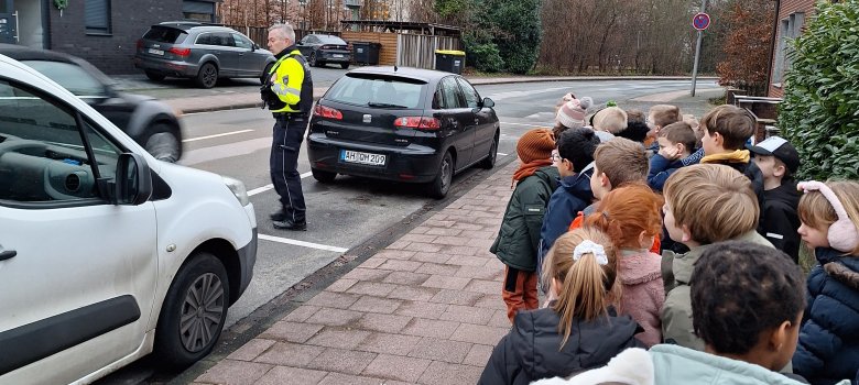 Polizist erklärt Kindern das richtige Überqueren der Straße