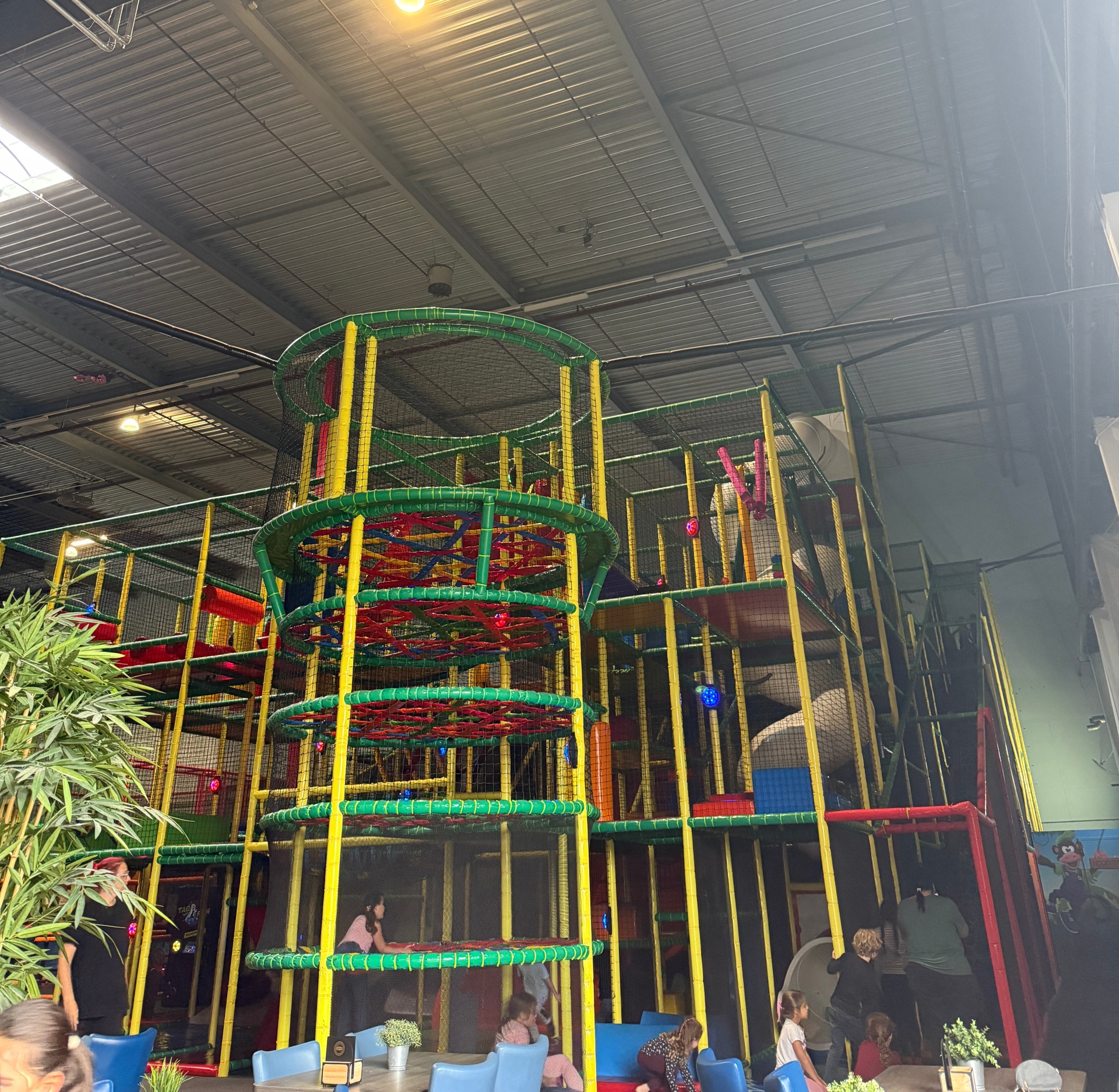 Das Foto zeigt einen bunten Kletterturm in einem Indoor Spielplatz mit verschiedenen Ebenen und Klettermöglichkeiten.