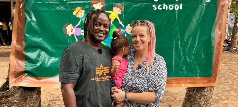 Janine Hundt mit Mann und Tochter vor dem Schulbanner